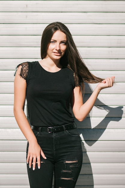 Une femme brune aux cheveux longs portant un t-shirt noir vierge