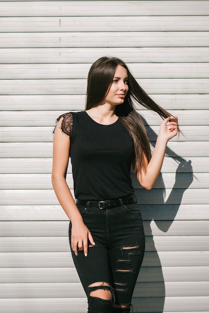 Une femme brune aux cheveux longs portant un t-shirt noir vierge