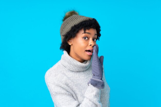 Femme brune avec un chapeau d'hiver sur fond bleu isolé