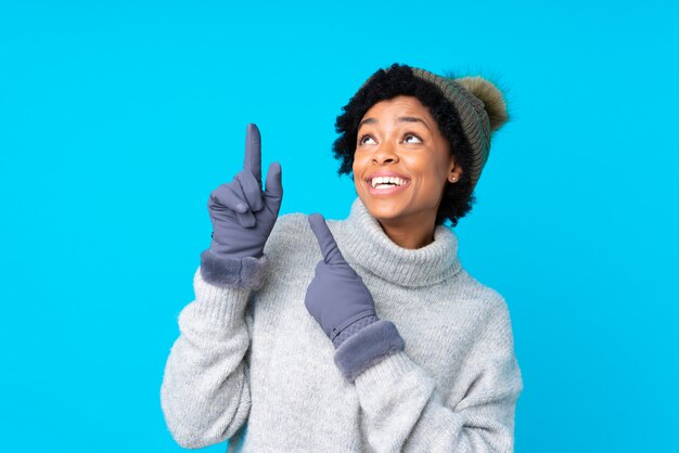 Femme brune avec un chapeau d'hiver sur fond bleu isolé