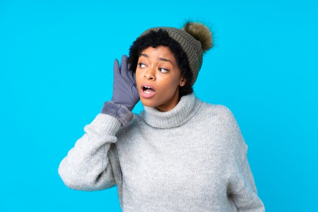 femme brune avec un chapeau d'hiver sur fond bleu isolé