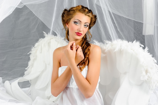 Une femme brune en costume d'ange pose devant la caméra.