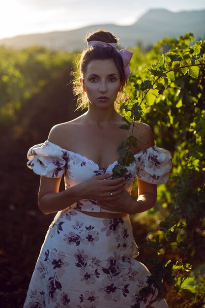 Femme brune dans une robe blanche se dresse dans un vignoble en été en Italie
