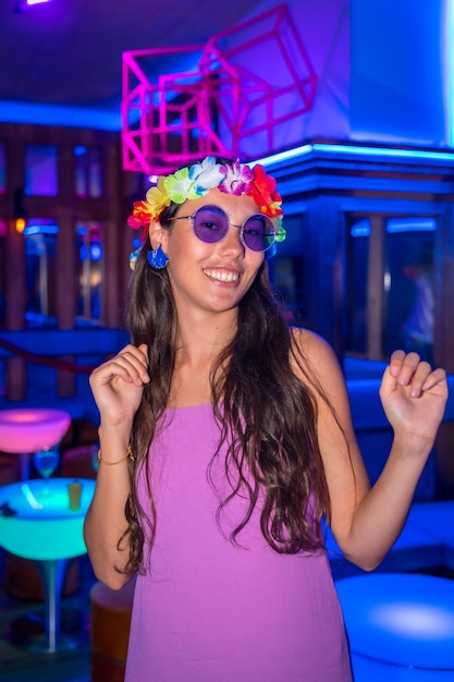 Femme brune dansant lors d'une soirée dans une boîte de nuit dans des verres violets lors d'une soirée dans un pub