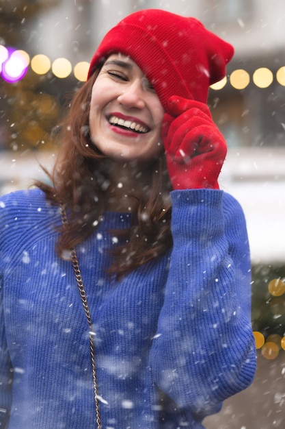 Femme brune drôle marchant à la foire de Noël pendant les chutes de neige