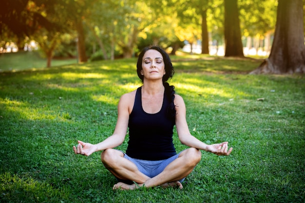 Femme brune faisant du yoga dans un parc