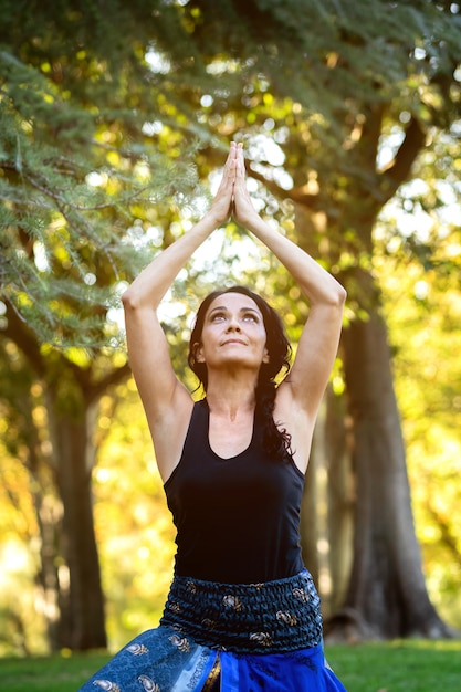 Femme brune faisant du yoga dans un parc