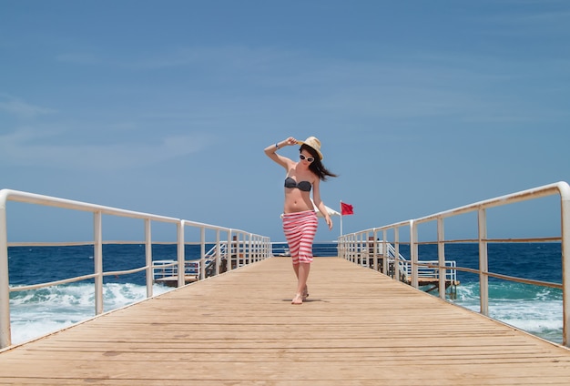 Femme brune sur la jetée à la mer