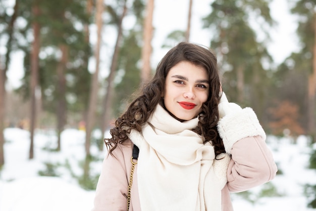 Une femme brune joyeuse aux cheveux longs porte un manteau en hiver. Espace pour le texte