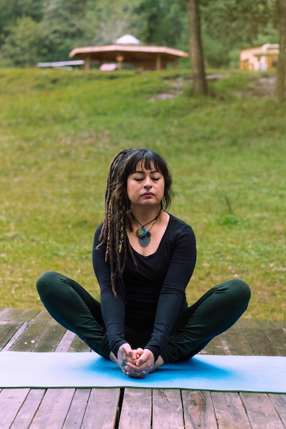 Femme brune latina en posture de lotus sur un tapis, méditation dans la forêt. Mode de vie.