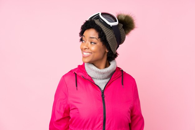 Femme brune avec des lunettes de neige sur fond rose isolé