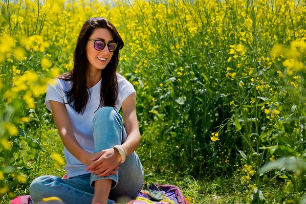 Femme brune à lunettes de soleil au milieu du champ fleuri