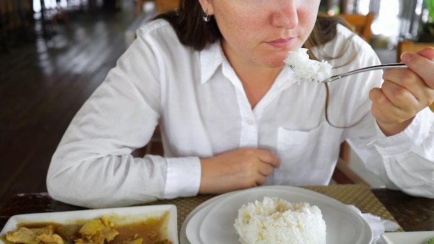 Femme brune mangeant du riz dans un café. Sur la viande de table avec des légumes.