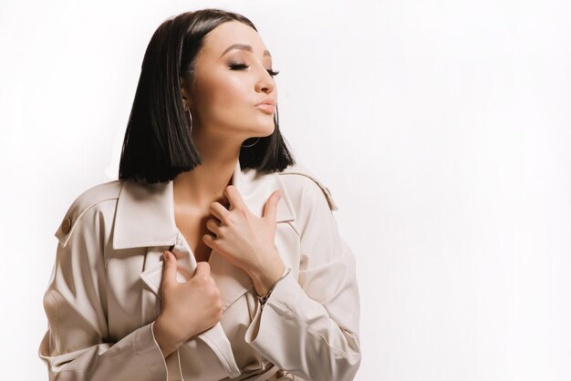 Femme brune en manteau posant sur fond blanc