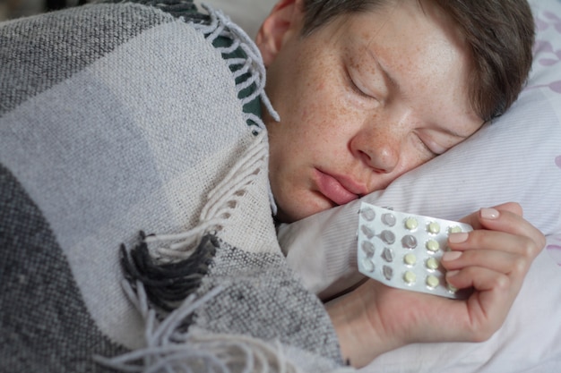 Femme brune mature dormir dans son lit sous une couverture à carreaux, concept de maladie ou de froid, traitement à domicile, mise au point sélective