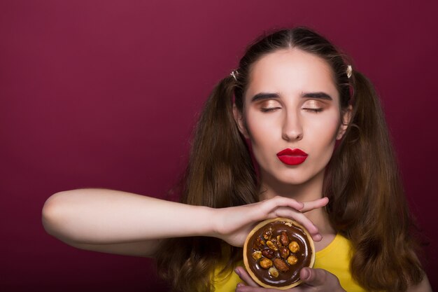 Femme brune à la mode tenant un délicieux dessert au chocolat sur fond rouge. Espace pour le texte