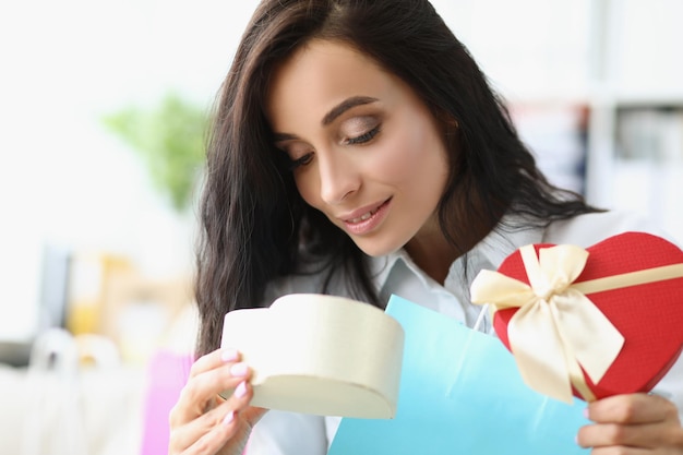 Une femme brune ouvre une boîte de fête et recherche un cadeau à l'intérieur d'un regard curieux