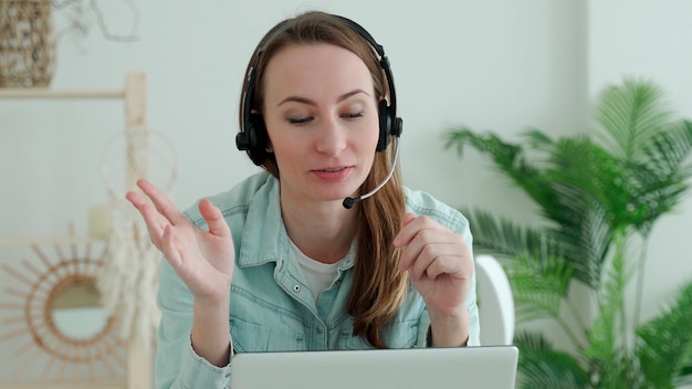 Femme brune porte un casque appelant sur un ordinateur portable parle avec un enseignant en ligne qui étudie, travaille à domicile