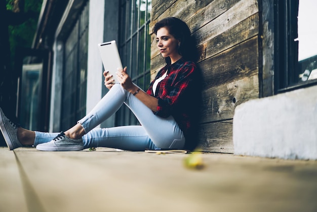 femme brune positive appréciant les loisirs tout en lisant des nouvelles intéressantes sur une page Web via un pavé tactile