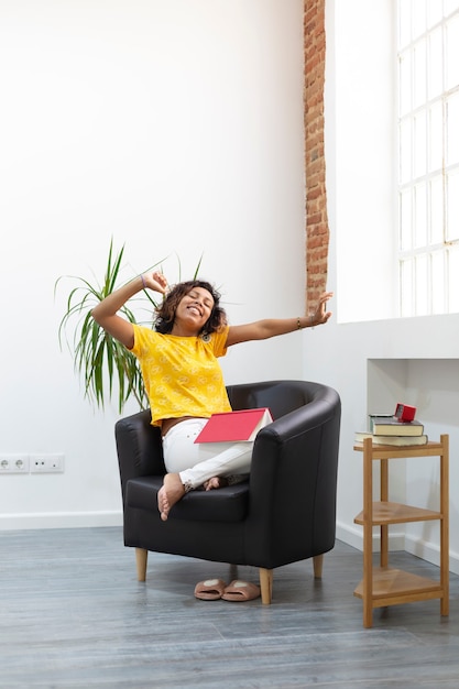 Femme brune prend une pause en lisant et étire ses bras. Espace pour le texte.