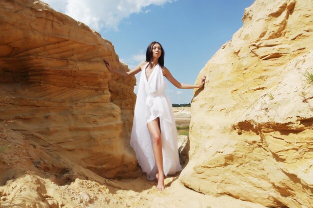 Femme brune en robe blanche dansant sur le désert