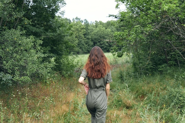 Femme brune en salopette sur la vue arrière du pré