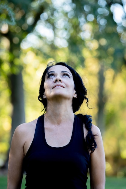 Femme brune songeuse, joyeuse une journée dans un parc