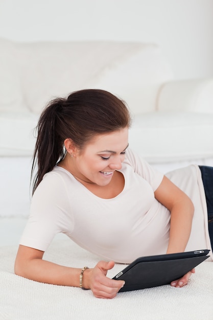 Femme brune souriante à l&#39;aide d&#39;une tablette