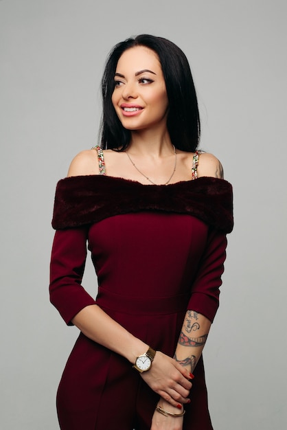 femme brune souriante dans une magnifique robe rouge avec fausse fourrure.