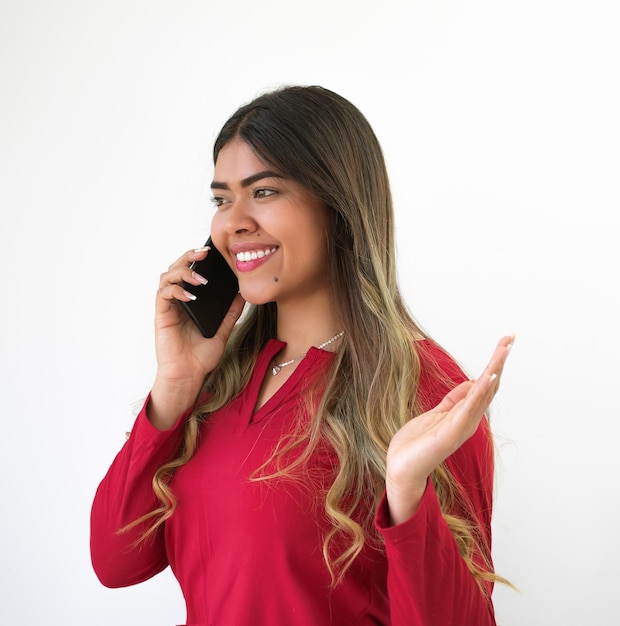 Photo une femme brune souriante avec un téléphone à la main avec un chemisier rouge ou un t-shirt rouge