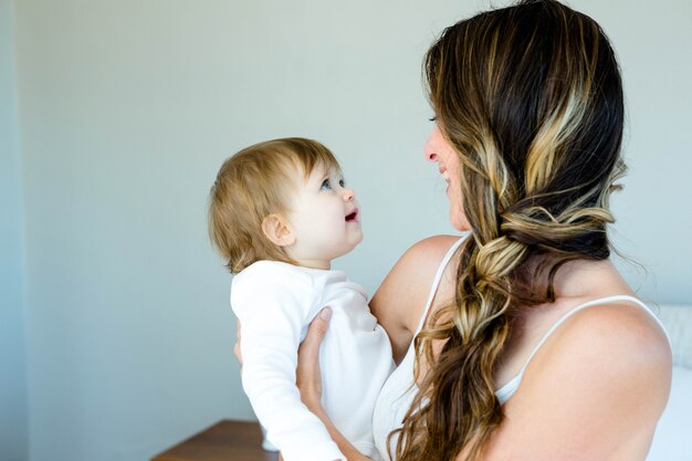 femme brune souriante tenant un adorable bébé aux yeux bleus