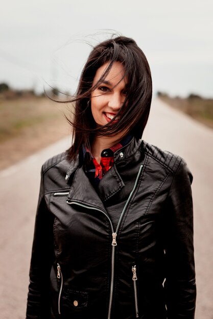 Femme brune avec veste en cuir noir dans une route