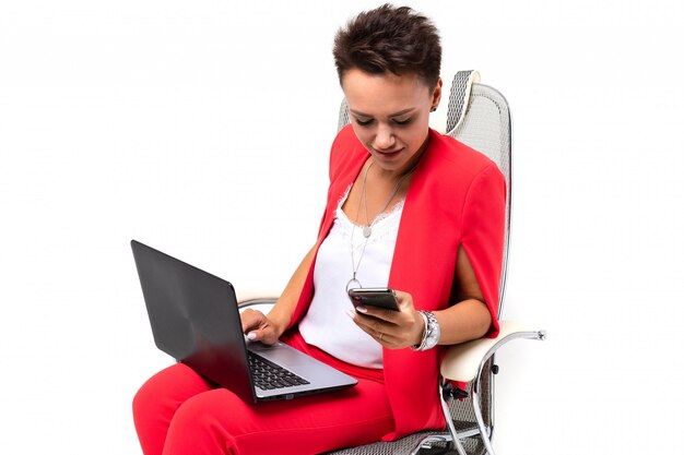 Femme de bureau est assis sur une chaise et résout les problèmes avec le téléphone et l'ordinateur portable