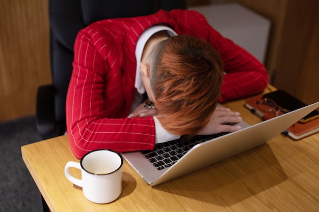 Une femme de bureau fatiguée qui dort sur le clavier de son ordinateur portable.