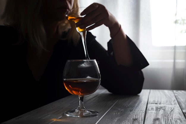 Femme buvant de l&#39;alcool seule en regardant par la fenêtre.