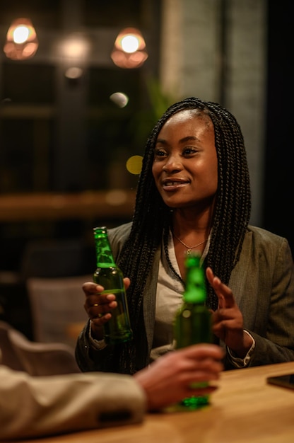 Femme buvant de la bière au bar avec ses collègues après le travail