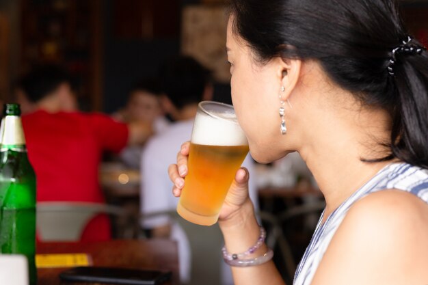 Femme buvant de la bière dans un restaurant en vacances.