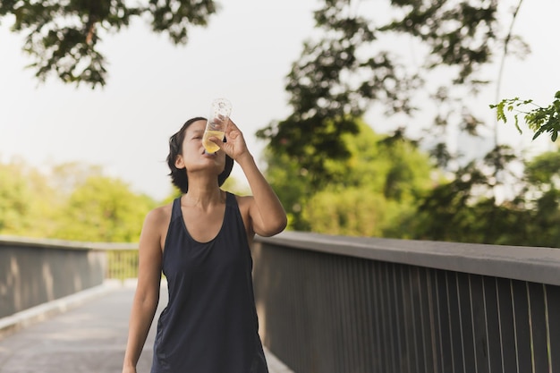 Photo femme buvant une boisson énergisante après un jogging dans le parc