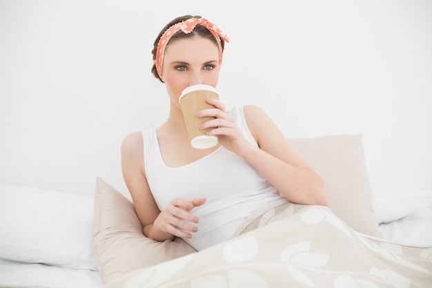 Femme buvant un café allongé dans son lit