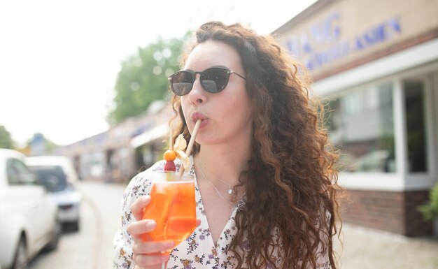 Femme buvant un cocktail à l'extérieur d'un bar
