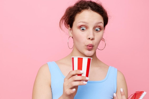 Femme buvant dans un verre jetable gros plan fond rose inchangé