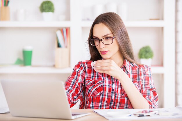 Femme buvant du café à l'aide d'un ordinateur portable