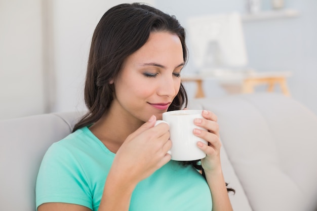 Femme buvant du café sur le canapé