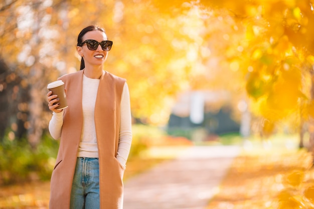 femme buvant du café dans le parc sous le feuillage d'automne