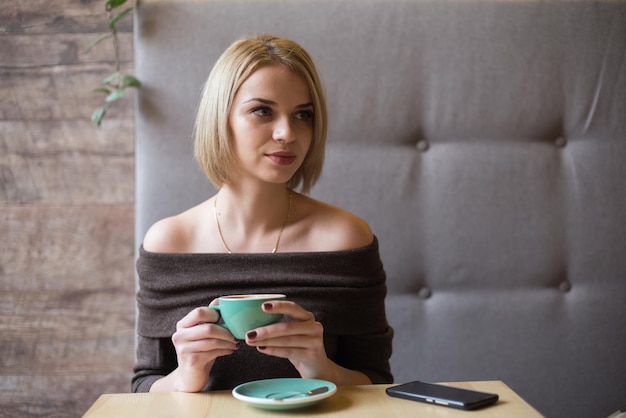 Femme buvant du café le matin au restaurant Soft focus sur les yeux Sellphone on table