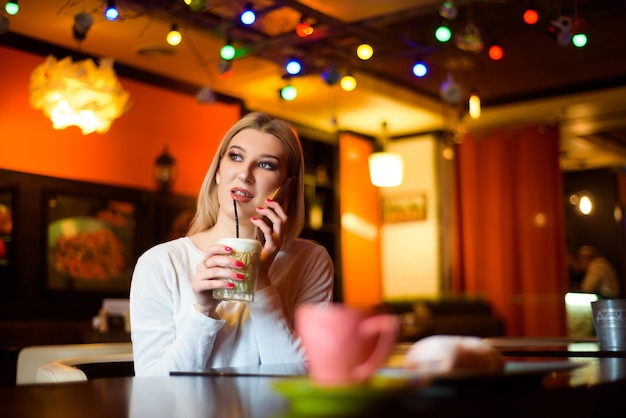 Femme buvant du café et parle au téléphone dans un café.