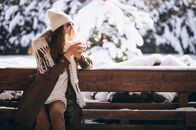 Femme buvant du café près de la maison en hiver