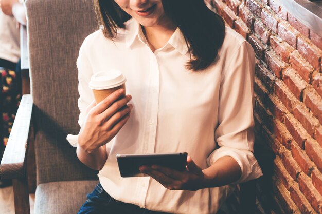 Femme buvant du café et travaille sur une tablette au café