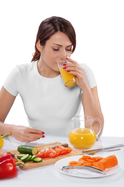 Femme buvant du jus assis près de la table avec des fruits isolés