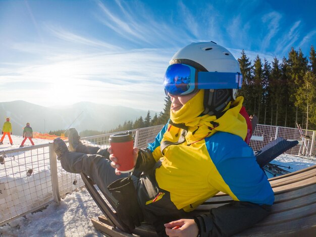 Photo femme buvant du thé chaud au sommet de la colline d'hiver avec vue sur le coucher de soleil ski et snowboard mode de vie